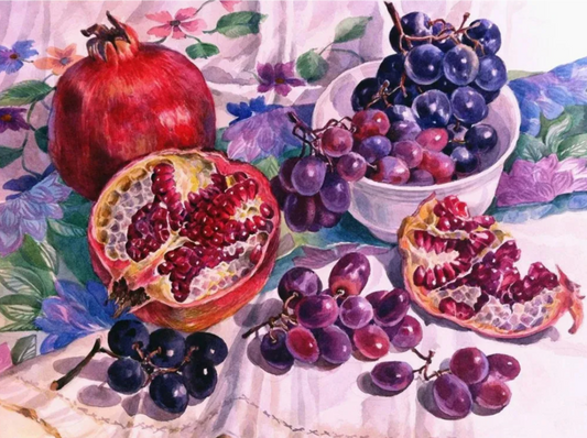 Still life painting of pomegranates and grapes on a floral tablecloth