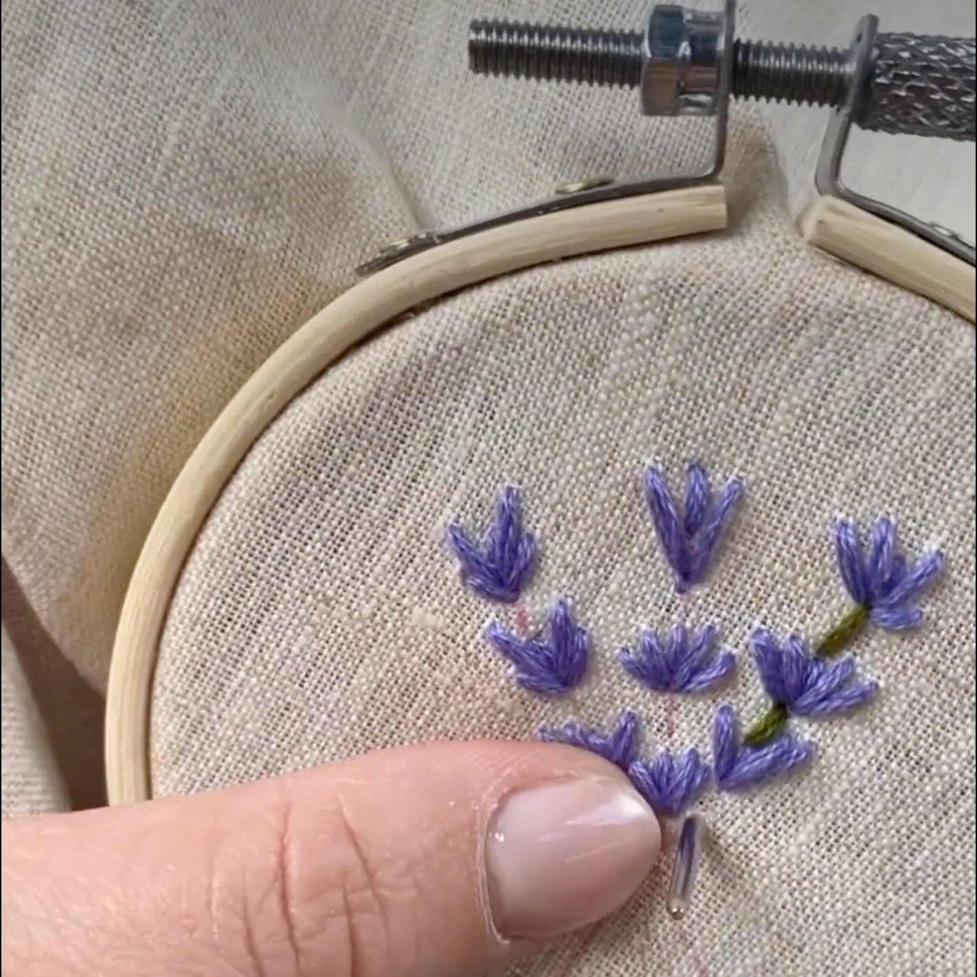 Hand embroidery with purple flowers on beige fabric