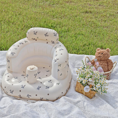 Inflatable Baby Sofa with a bunny design, placed on a picnic blanket outdoors, accompanied by a teddy bear and a basket of flowers.