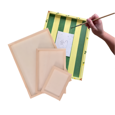 Set of wooden frames with a green striped frame and a hand holding a paintbrush.